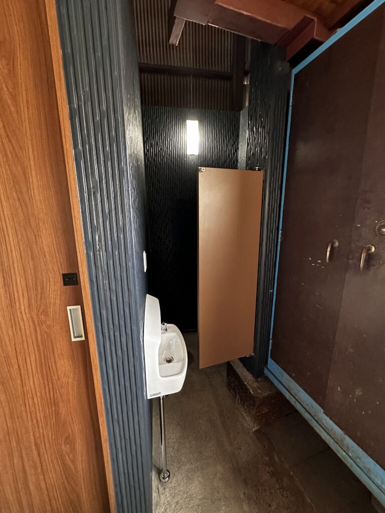 こちらが、新・男性小用の外観です。ガラッと雰囲気が変わりましたね♪このスイングドアの枠を取り付ける為に柱に穴を開けているのですが、実は私が開けました。厚みのあるH形鋼だったので業者さんの道具では歯が立たないとのことでしたが、私たちは鉄工所ですので、お安い御用でした。とはいえ8か所に穴を開けるのは結構しんどかったですw